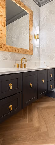 Powder room with black vanity and brass mirror