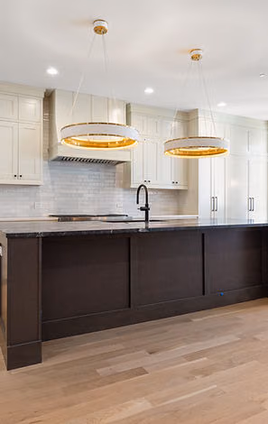Kitchen with dark island and gold pendant lights