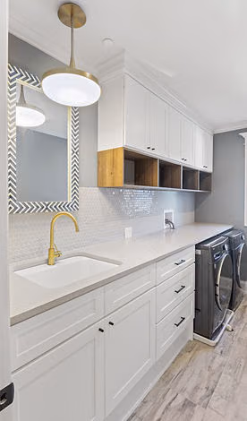 Laundry room with white cabinetry and brass faucet